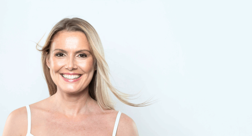 Smiling middle-aged woman with smooth skin and natural look, representing refreshed and confident results of anti-wrinkle injections.