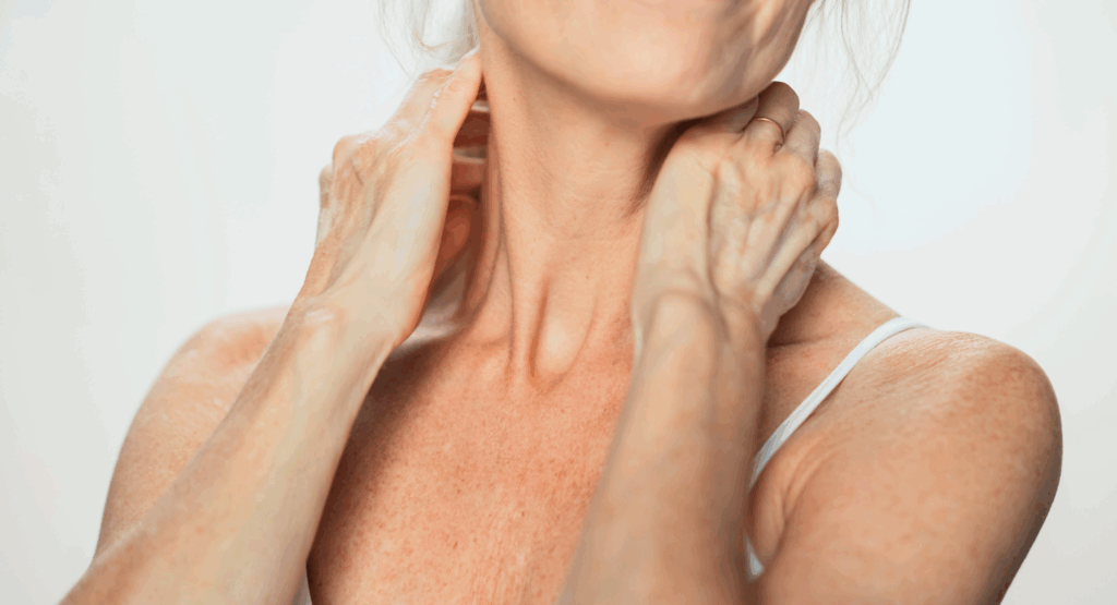 Close-up of mature woman gently touching neck and décolletage – highlighting skincare for neglected areas in Look Lovely London’s guide to caring for the neck, chest, and hands.