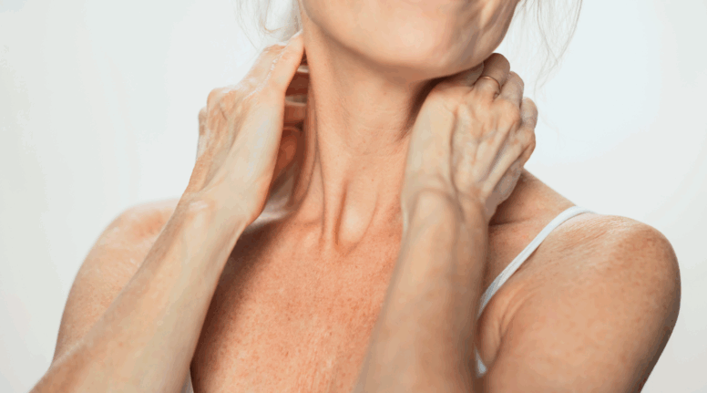 Close-up of mature woman gently touching neck and décolletage – highlighting skincare for neglected areas in Look Lovely London’s guide to caring for the neck, chest, and hands.