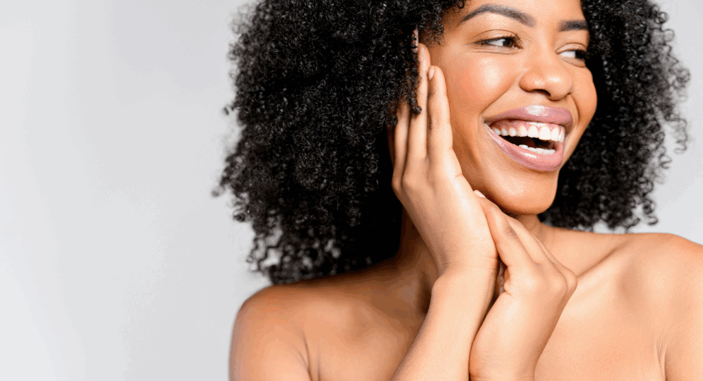 Radiant woman with glowing skin and natural curls smiling joyfully – featured in Look Lovely London’s blog on science-backed tips for achieving real skin glow.